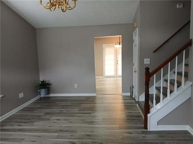 entryway with a chandelier, wood finished floors, stairway, and baseboards