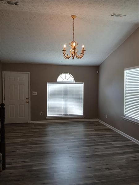 unfurnished room featuring a chandelier, baseboards, dark wood-style floors, plenty of natural light, and a textured ceiling