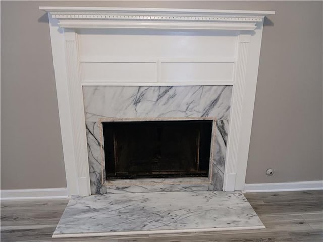 detailed view of a fireplace, wood finished floors, and baseboards