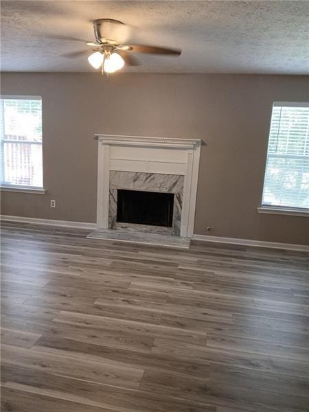 unfurnished living room featuring baseboards, a textured ceiling, and plenty of natural light