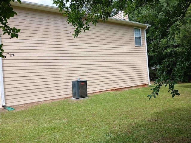 view of property exterior with cooling unit and a yard