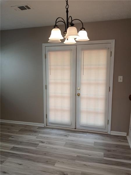 entryway featuring a chandelier, light wood-type flooring, baseboards, french doors, and plenty of natural light