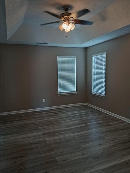 unfurnished room with a tray ceiling, baseboards, and dark wood-style floors