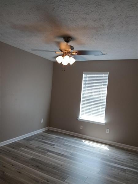 unfurnished room featuring ceiling fan, wood finished floors, baseboards, and a textured ceiling