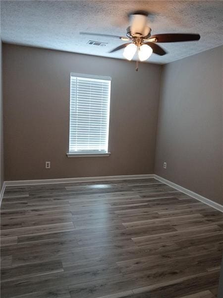 unfurnished room with ceiling fan, a textured ceiling, dark wood-type flooring, and baseboards