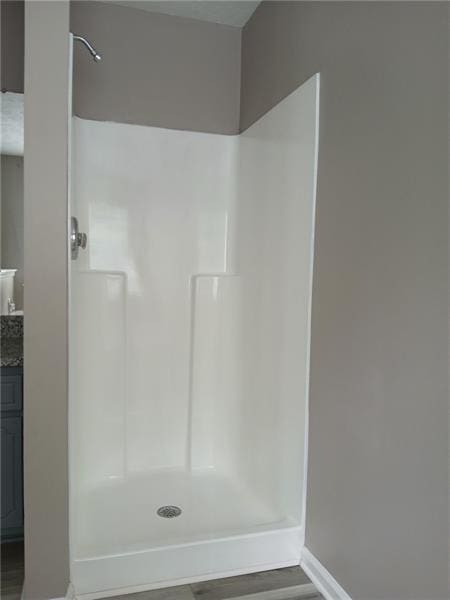 bathroom featuring baseboards, a walk in shower, and wood finished floors