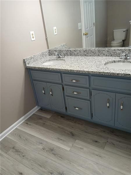 full bathroom with toilet, double vanity, and wood finished floors