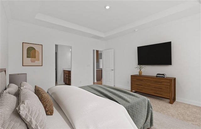 carpeted bedroom featuring a tray ceiling and ensuite bath