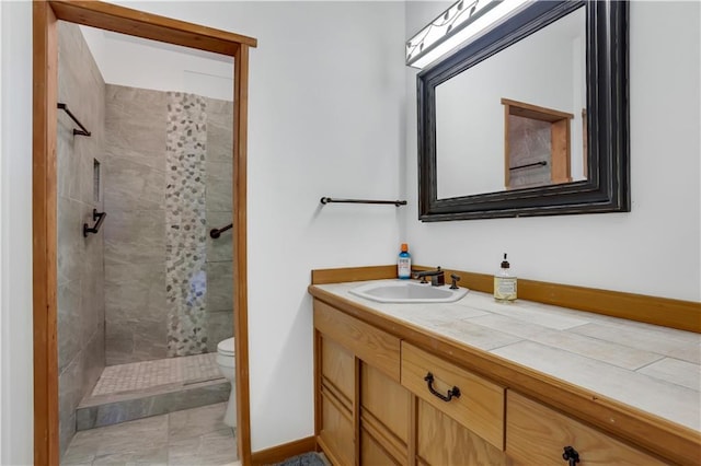 bathroom featuring a tile shower, vanity, and toilet