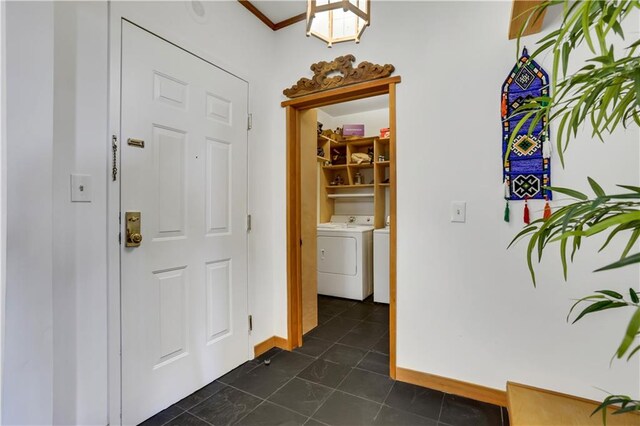 hallway featuring ornamental molding, washer and dryer, and dark tile patterned floors