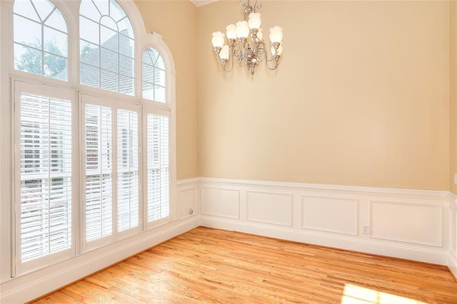 1595 Lake Lucerne Rd SW, Lilburn, GA 30047 - spare room with a chandelier, light wood-style flooring, and wainscoting