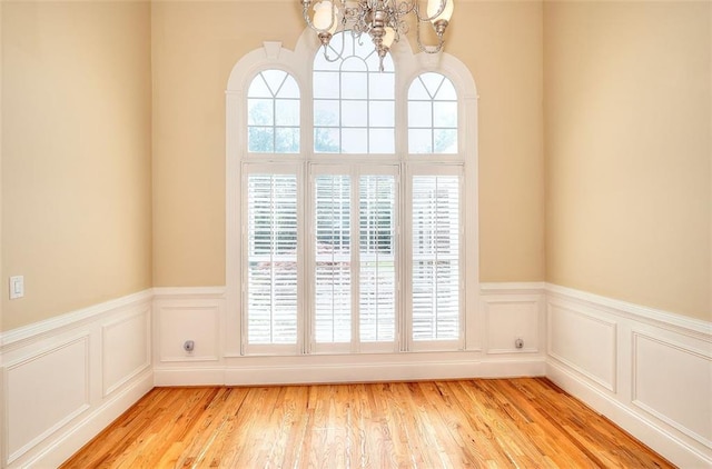 1595 Lake Lucerne Rd SW, Lilburn, GA 30047 - unfurnished room with a chandelier, a wainscoted wall, light wood-style floors, and a decorative wall