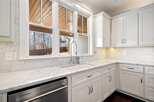 kitchen featuring sink, dishwasher, white cabinetry, backsplash, and light stone countertops