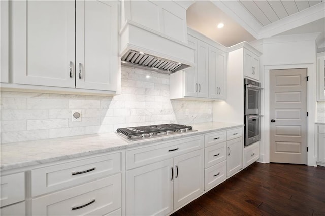 kitchen with light stone counters, stainless steel appliances, white cabinets, and premium range hood