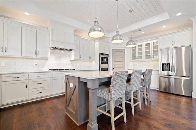 kitchen with a kitchen island, appliances with stainless steel finishes, white cabinets, and a tray ceiling