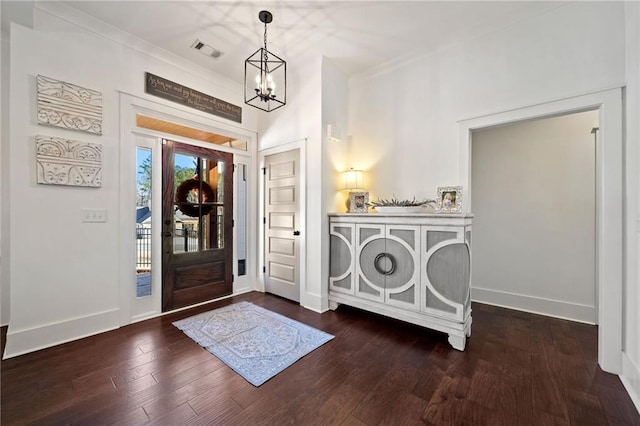 entryway with crown molding, an inviting chandelier, and dark hardwood / wood-style flooring