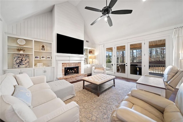 living room with built in features, french doors, ceiling fan, a brick fireplace, and light hardwood / wood-style flooring