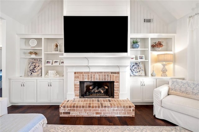 living room with vaulted ceiling, dark hardwood / wood-style floors, a fireplace, and built in shelves