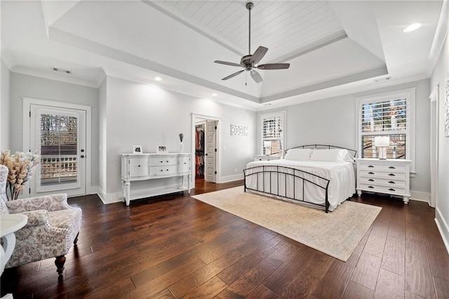 bedroom with dark hardwood / wood-style floors, ornamental molding, a tray ceiling, and access to exterior