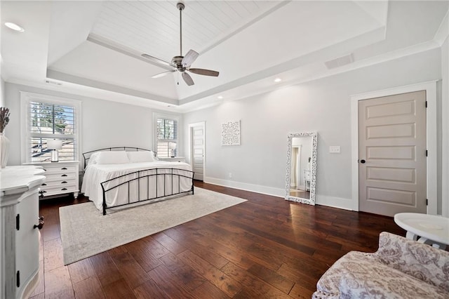 bedroom featuring multiple windows, a tray ceiling, and dark hardwood / wood-style floors