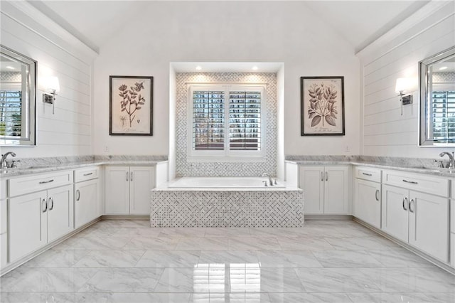 bathroom featuring lofted ceiling, vanity, and a relaxing tiled tub