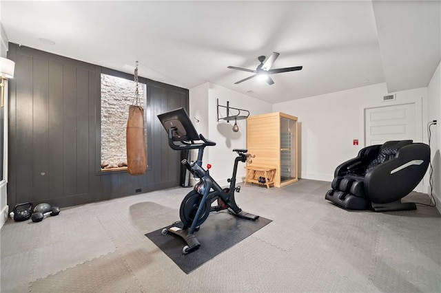 workout room featuring ceiling fan and wooden walls