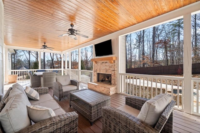 wooden deck with ceiling fan and an outdoor living space with a fireplace