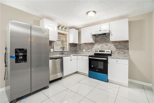 kitchen with appliances with stainless steel finishes, marble finish floor, under cabinet range hood, white cabinetry, and a sink