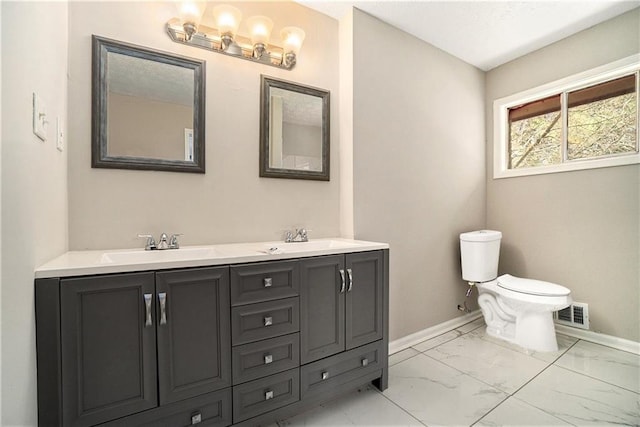 full bathroom with double vanity, baseboards, toilet, marble finish floor, and a sink