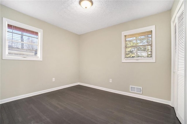 unfurnished bedroom with visible vents, a textured ceiling, baseboards, and multiple windows