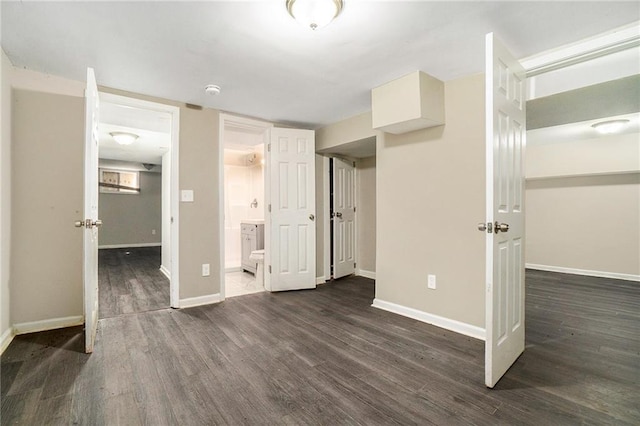 unfurnished bedroom with dark wood-type flooring, ensuite bath, and baseboards