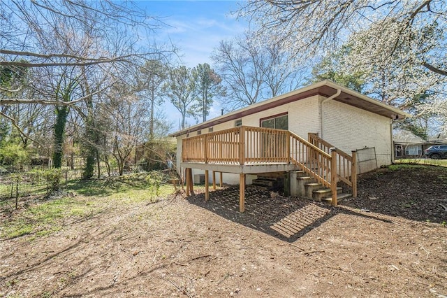 back of property featuring stairway, fence, a deck, and brick siding