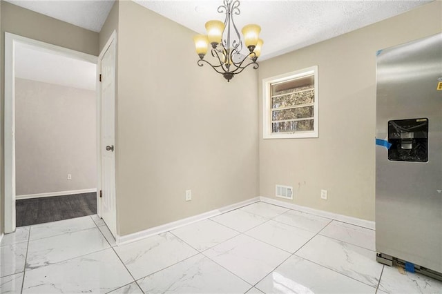 unfurnished dining area with a textured ceiling, a notable chandelier, visible vents, baseboards, and marble finish floor