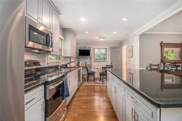 6590 Williamson Dr NE, Atlanta, GA 30328 - kitchen featuring stainless steel appliances, a sink, crown molding, dark wood-style floors, and dark stone counters
