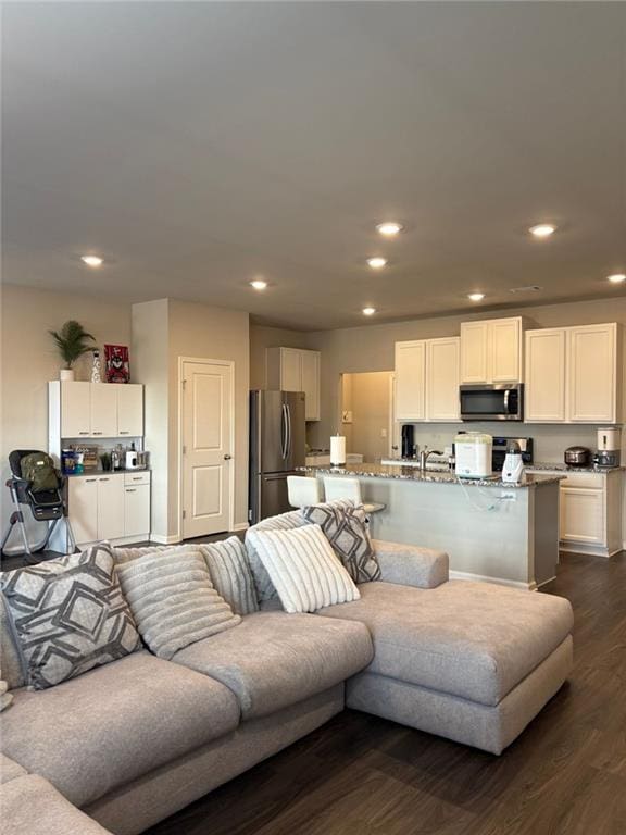 living area with dark wood-type flooring and recessed lighting