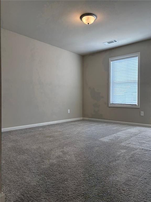 carpeted spare room with visible vents and baseboards