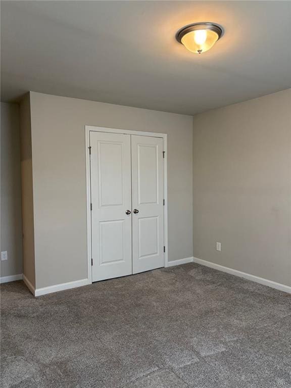 unfurnished bedroom featuring carpet, a closet, and baseboards