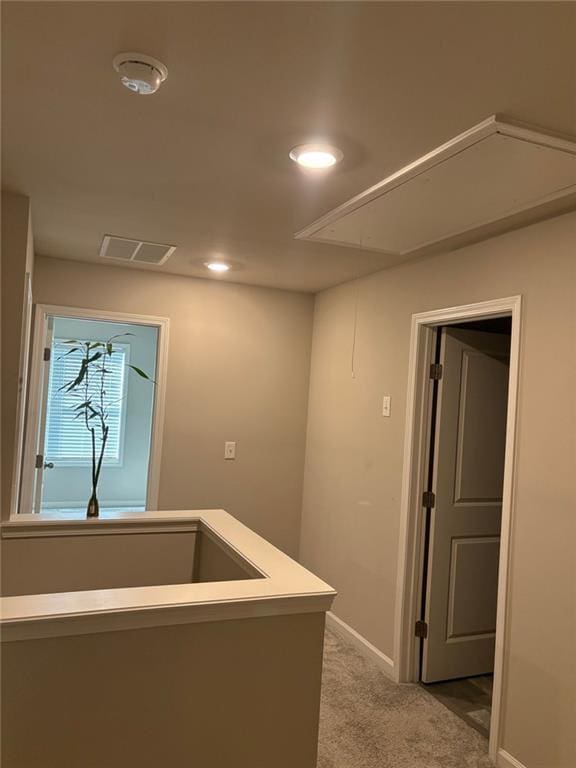 hallway featuring attic access, visible vents, baseboards, carpet floors, and recessed lighting