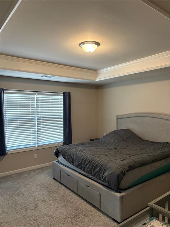 carpeted bedroom with ornamental molding, a raised ceiling, and baseboards