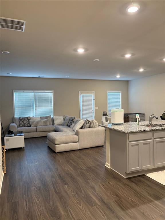 living room featuring recessed lighting, dark wood-style flooring, and visible vents