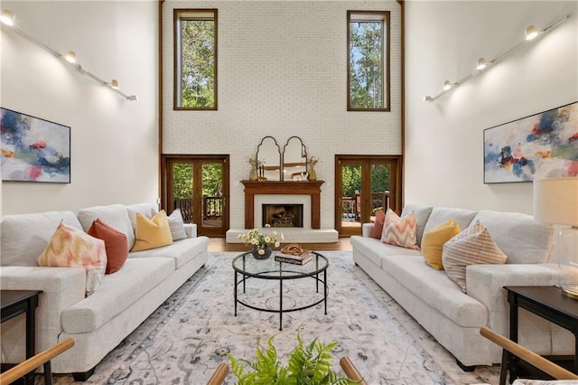 living room with a brick fireplace, a towering ceiling, french doors, and brick wall