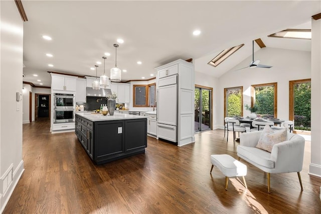 kitchen with white cabinetry, paneled refrigerator, decorative light fixtures, and a center island