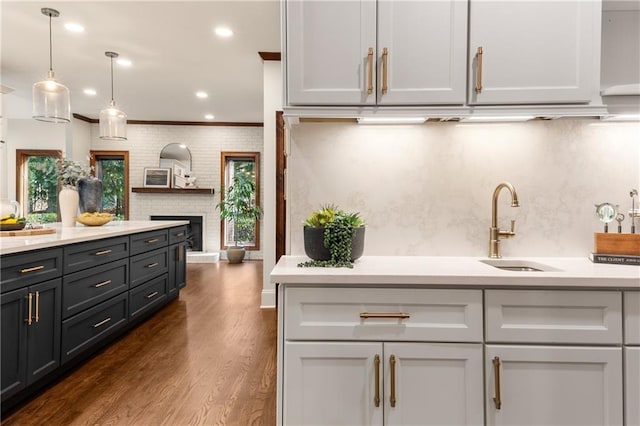 kitchen with sink, crown molding, dark hardwood / wood-style floors, a fireplace, and decorative light fixtures