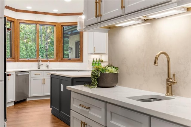 kitchen with dishwasher, ornamental molding, sink, and light wood-type flooring