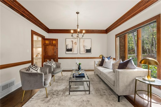 living room featuring ornamental molding, plenty of natural light, a notable chandelier, and light hardwood / wood-style flooring