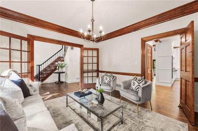 living room featuring an inviting chandelier, wood-type flooring, and ornamental molding