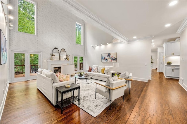 living room with crown molding, brick wall, a healthy amount of sunlight, and dark hardwood / wood-style flooring