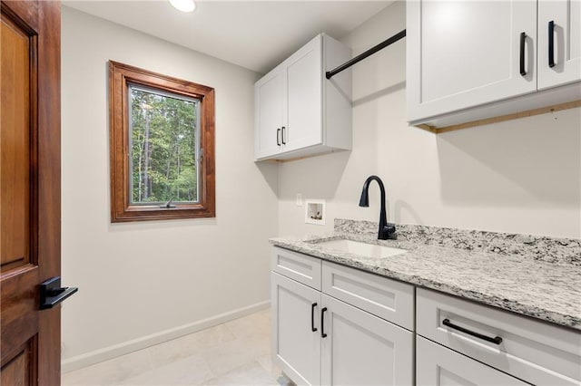 laundry room featuring sink, hookup for a washing machine, cabinets, and light tile patterned floors