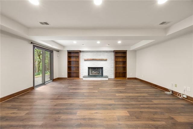 unfurnished living room with dark wood-type flooring, a fireplace, and a raised ceiling