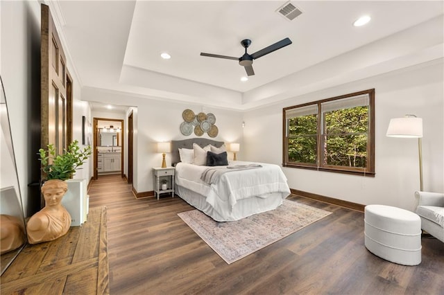 bedroom with ceiling fan, a tray ceiling, and dark hardwood / wood-style flooring